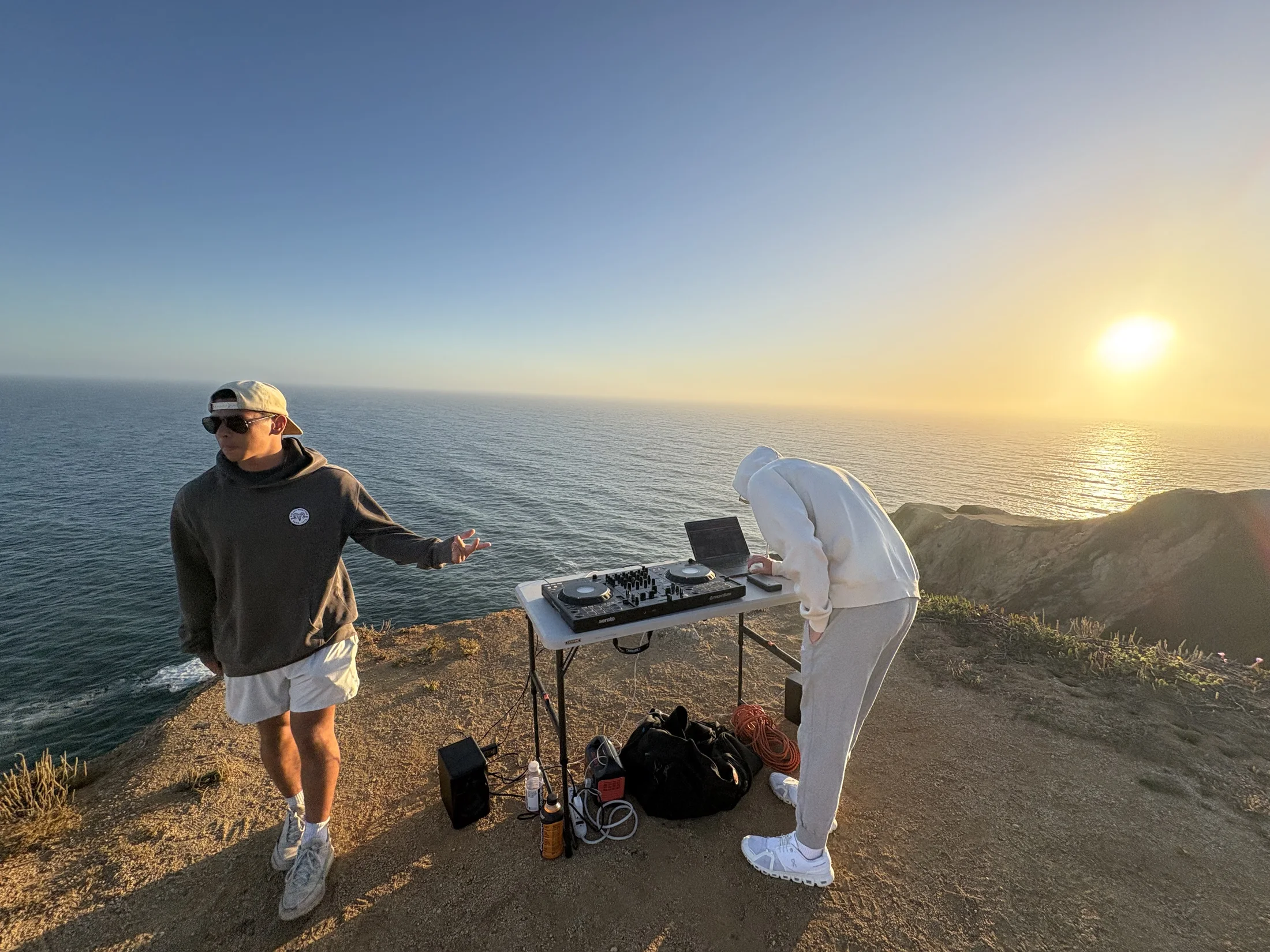 Two DJs playing a sunset set above the Pacific Ocean