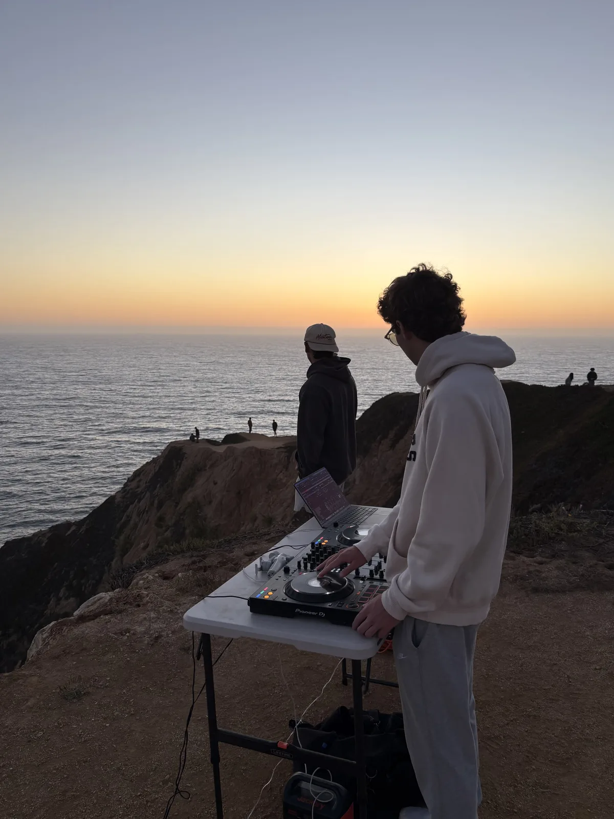 Alex performing beside the ocean at sunset
