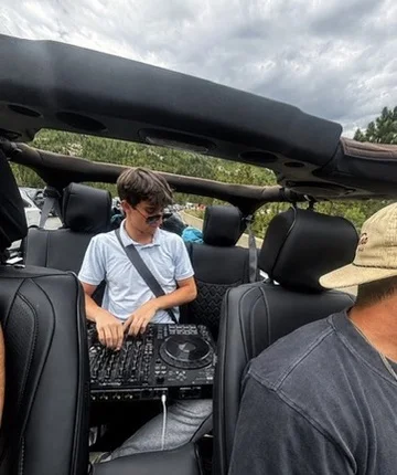 Alex DJing from the back seat of an open-top vehicle